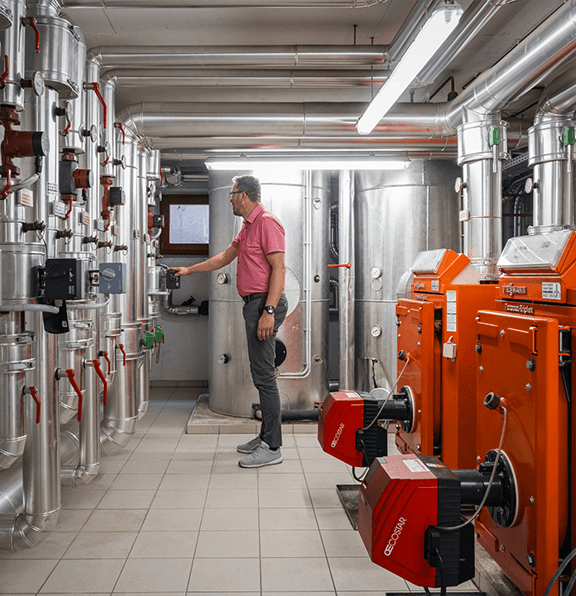 Techniker bei der Wartung einer modernen Heizungsanlage mit effizienten Heizkesseln und Rohrsystemen.