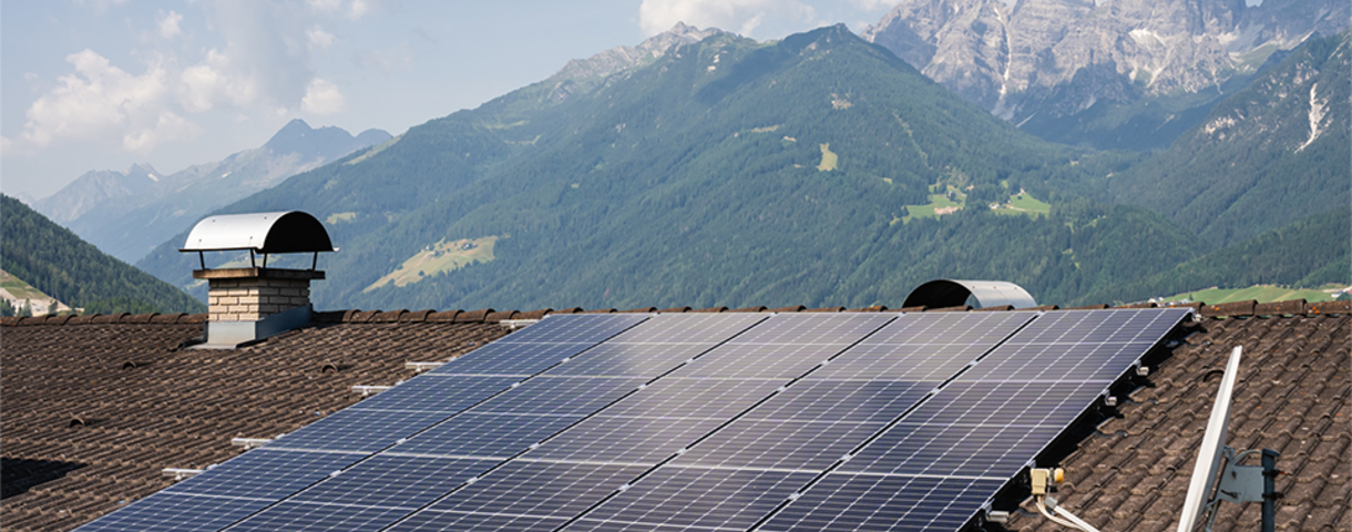 Photovoltaik-Anlage auf Dach mit Bergen im Hintergrund